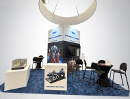 Exhibit booth design with an overhead ring sign and meeting tables