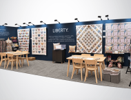 Liberty exhibit booth design with quilt displays and wooden tables